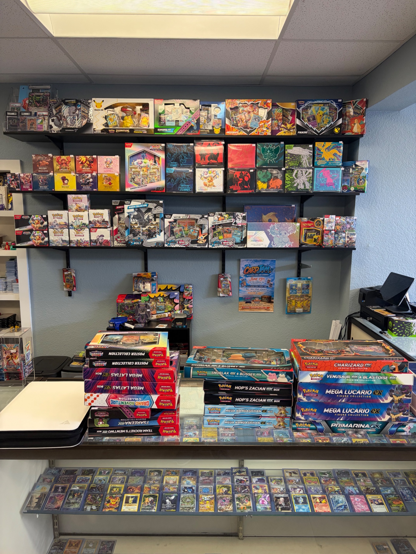 Heavy Cards showcase counter stacked with Pokémon sealed product and singles tray below
